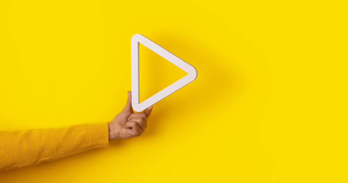 hand holding play button on yellow background